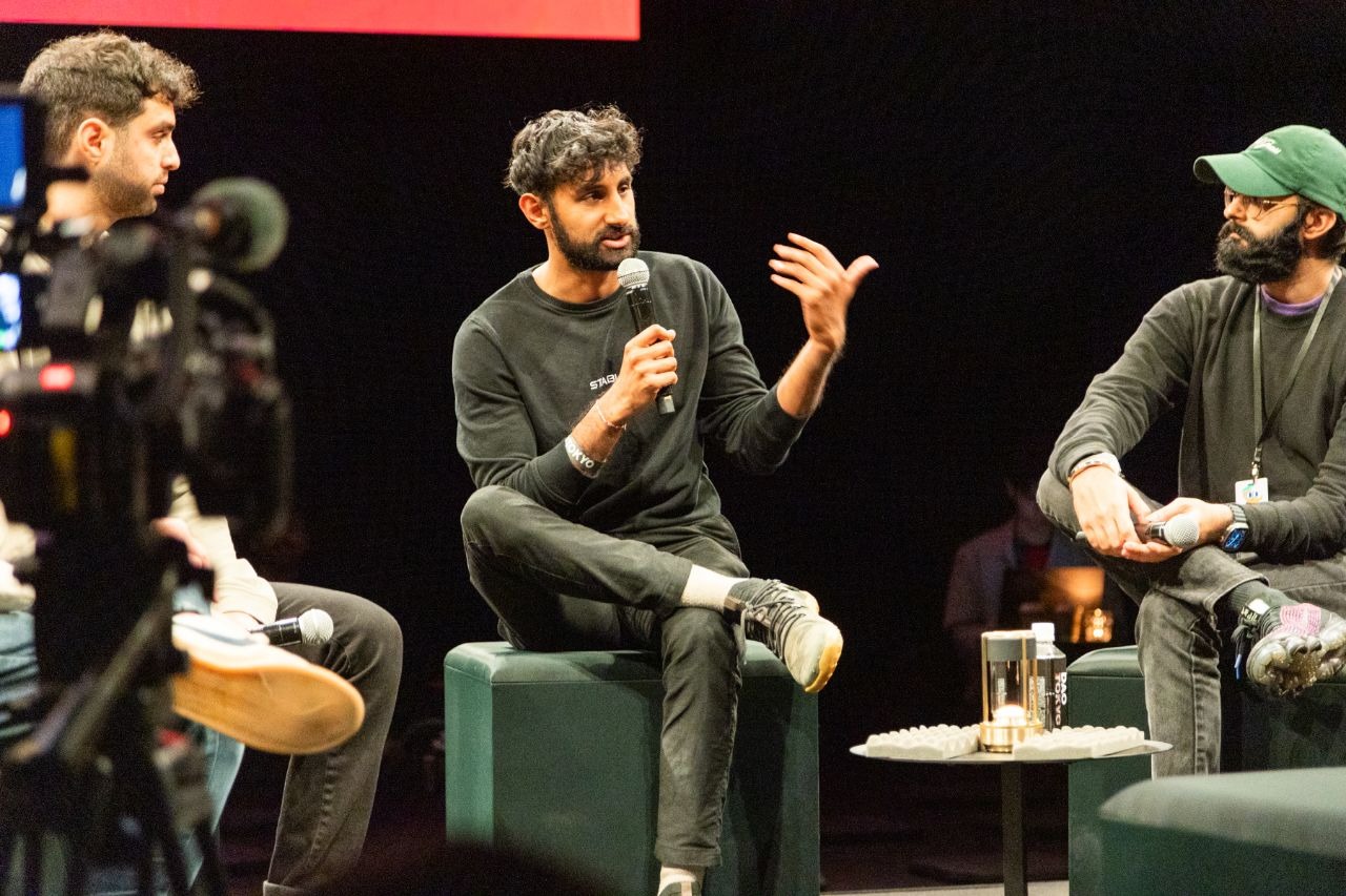 Speaking into a microphone while seated on a panel on a darkened stage